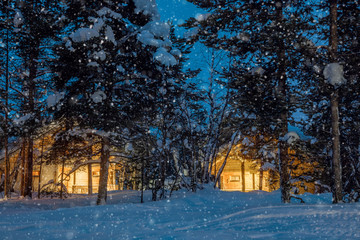 Wintersnowfall night, small wooden houses with warm light