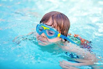 Little kid boy making swimming competition in pool