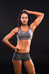 Fototapeta na wymiar Fitness concept. Picture of beautiful brunette fitness or sports lady looking at camera while demonstrating her perfect abs and body in general.