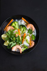 asian rice noodle, shrimps and vegetable soup in bowl