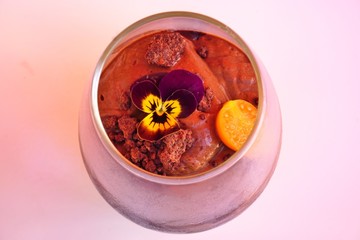 Vegan chocolate mousse decorated with a pansy flower in a clear glass