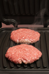 two fried cutlets on the grill with smoke