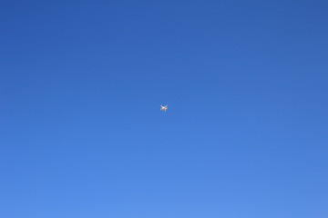 white drone hovering in a bright blue sky