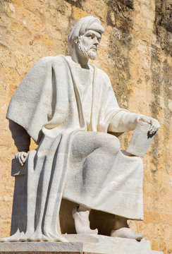 CORDOBA, SPAIN - MAY 25, 2015: The statue of medieval arabic philosopher Averroes by Pablo Yusti Conejo (1967) and the medieval walls.