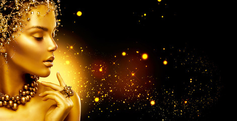 Golden woman. Beauty fashion model girl with golden make up, hair and jewellery on black background