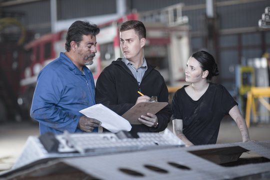 Mechanics working at fire brigade workshop reading check list
