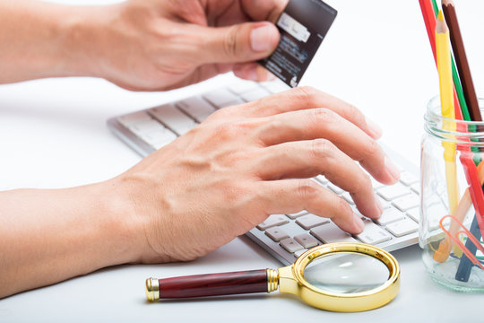 Person entering number of credit card with white workspace