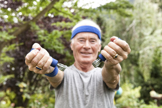 Senior man doing fitness training with gripper in his garden