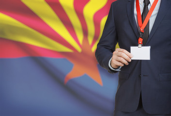 Businessman holding badge on a lanyard with USA state flag on background - Arizona