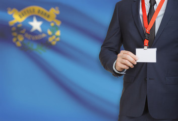 Businessman holding badge on a lanyard with USA state flag on background - Nevada