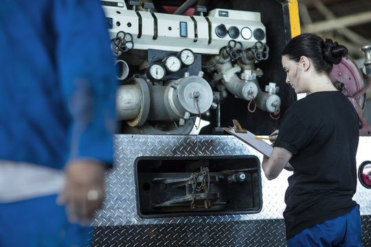 Mechanics working at fire brigade workshop checking check list