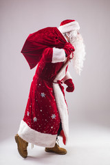 Cheerful man santa claus holding gift sack and move