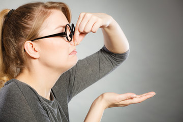 Girl pinches her nose because of stench stink.