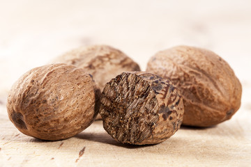 Nutmeg , whole and half on wooden plank, close up