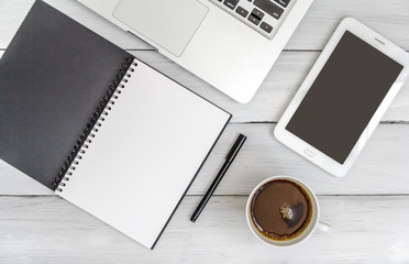 White office desk with laptop, smartphone, notebook on wooden table. Top view with copy space. Student or business accessories flatlay. Office supplies and gadgets on background. View from above.