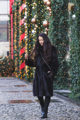 Happy woman walking in a black mink coat in city, beautifully de