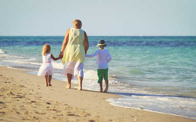 Happy grandmother with kids- little boy and girl- at beach