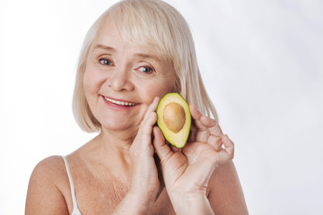 Delighted senior woman holding an avocado