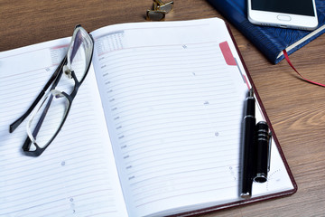 Business accessories on desktop: notebook, diary, fountain pen.