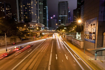 Night city streets with cars driving at crossroad with urban structures
