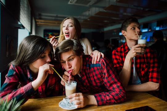 Group of young friends hanging out at a coffee shop. Young men and women meeting in a cafe having fun and drinking coffee. Lifestyle, friendship and urban life concepts.
