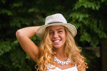 Smiling girl with white necklace and straw hat
