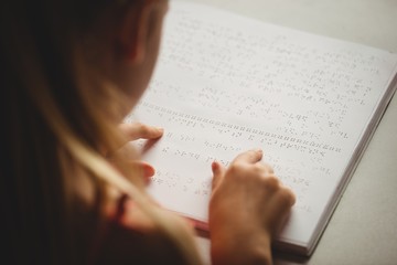 Girl using braille to read - obrazy, fototapety, plakaty