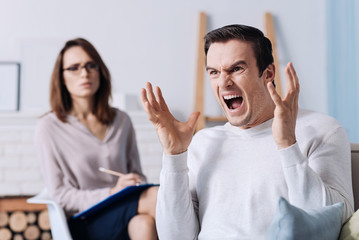 Emotional man screaming while consulting with psychologist