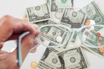 diverse currency through glasses, focused and blurry money on white backgrounds