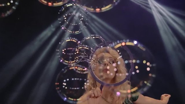 Woman is doing soap bubble show on the black background