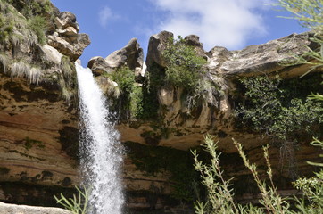Cascada de agua en montaña bajo cielo azul