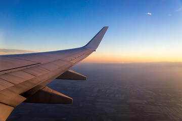 Wing of the air plane on the sea of clouds sunset sky background