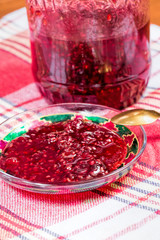 Raspberry jam in a glass bowl on a checkered tablecloth