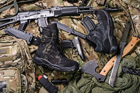 Military clothing-shoes and variety of weapons.Top view/Army boots, ax, gun, machete, knife and rifle top view.Selective focus