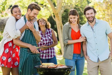 Happy friends preparing a barbecue grill in park