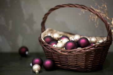 shiny and matt Christmas tree toys silver and vinous colors in a wicker basket with a branch of the tree