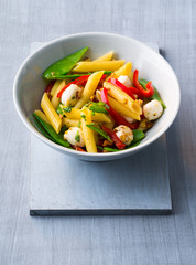 Penne with red pepper, sugar snaps, in a white bowl