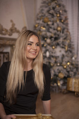 Fototapeta premium The pretty girl next to the fireplace and Christmas tree