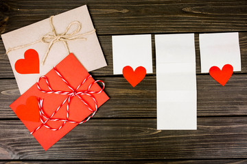 white leaflets and red envelope lying on wooden surface