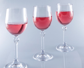Pink wine in stemmed glasses on white background