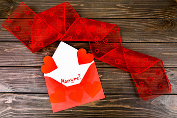 envelope with hearts and red tape lying on wooden surface