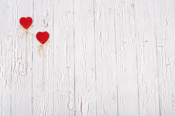 Red hearts with ropes lie on white wooden floor