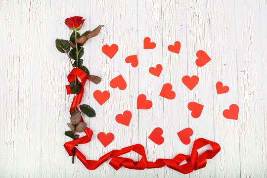 Red rose with long red silk ribbon surrounded with paper hearts
