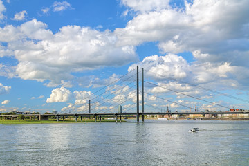 Fototapeta na wymiar Rheinkniebrucke cable-stayed bridge over the Rhine on the background of beautiful cumulus clouds in Dusseldorf, Germany