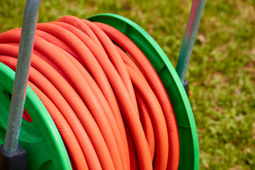 coil with orange rubber hose in the garden with green grass