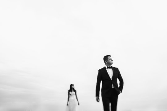 Black and white photo of thoughtful groom looking far away while