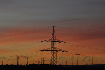 Strommast und Windr&auml;der bei Sonnenuntergang
