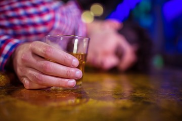 Man with whiskey glass lying on bar counter