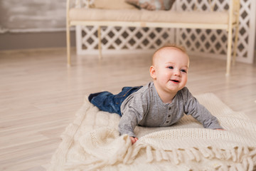 Adorable laughing baby boy in white sunny bedroom. Newborn child relaxing. Family morning at home.