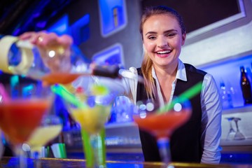 Smiling bartender pouring drink in glass